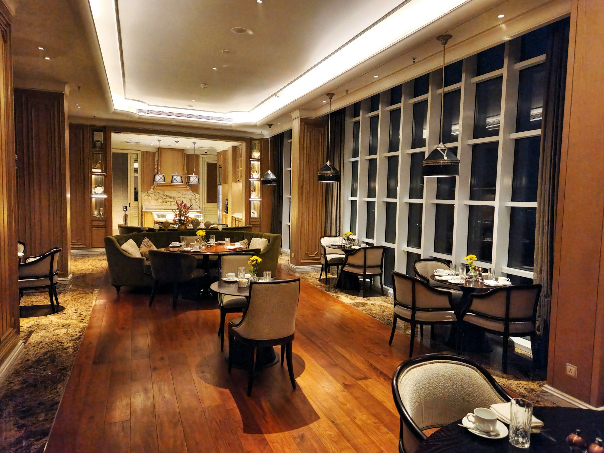 Gastraum eines Restaurants mit Holzboden, gedeckten Tischen und hohen Fenstern