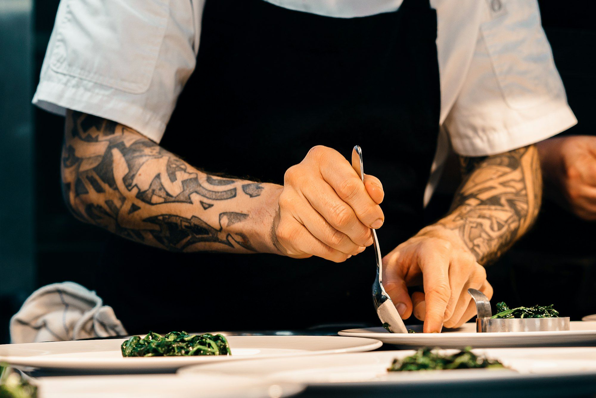 Hände richten in einer Restaurantküche Gerichte auf Tellern an
