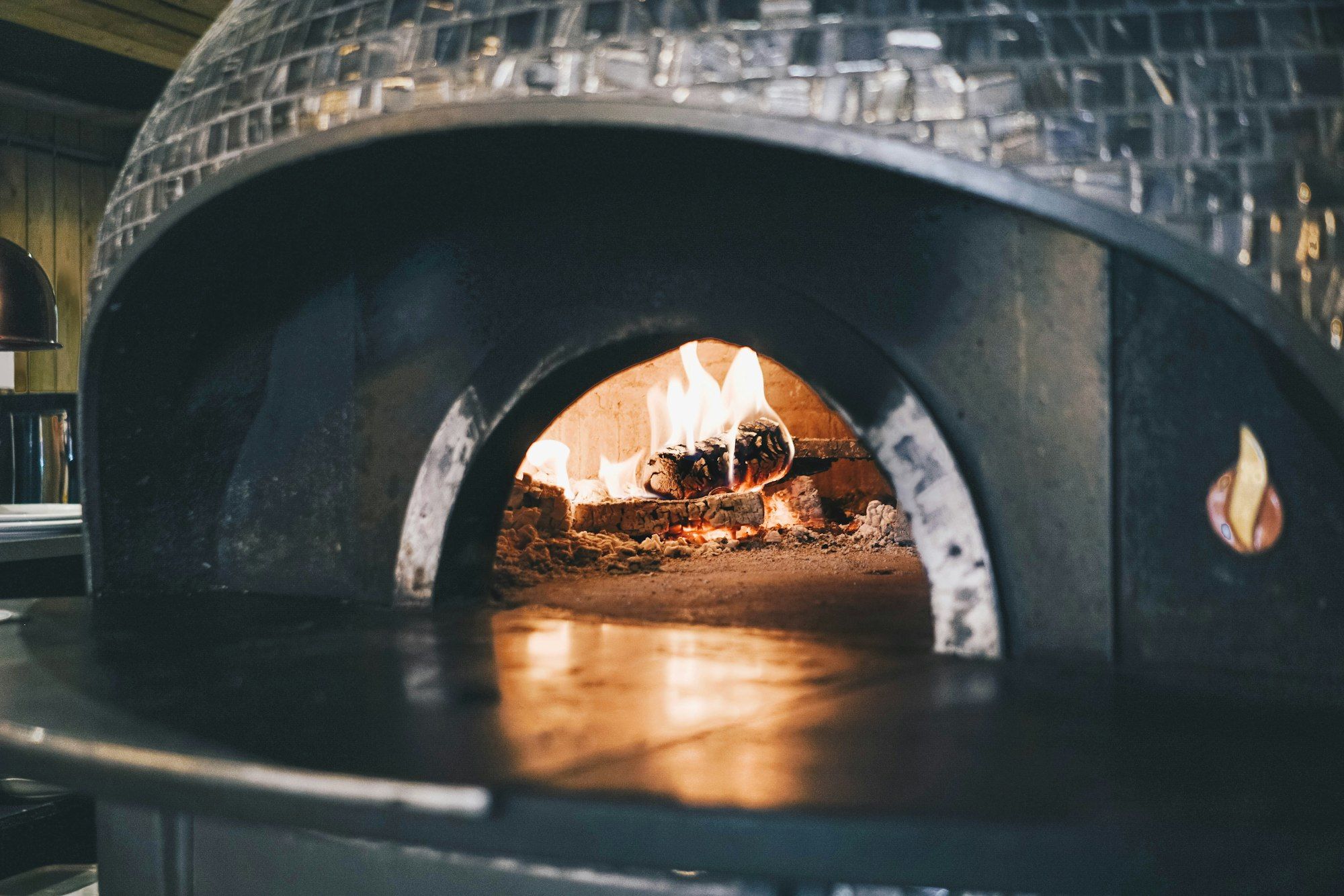 Holzbefeuerter Pizzaofen mit Flammen im Inneren